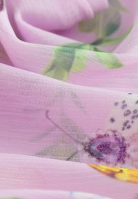 Leichtes, durchscheinendes lavendelfarbenes Gewebe mit floralen Mustern in Grün und Lila, das eine weiche Textur und feine Webart aufweist.