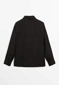 Chemise noire à manches longues en lin. Dispose d'un col classique et de poignets boutonnés, avec une texture lisse et une coupe décontractée.