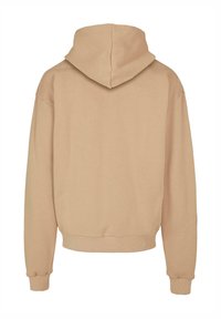 Felpa beige con una texture morbida, tasca a marsupio e maniche lunghe con polsini a coste. Il design include un cappuccio ampio e strutturato.