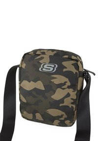Bolso bandolera de camuflaje fabricado con un tejido duradero, que cuenta con un cierre de cremallera y una correa negra ajustable. Logotipo visible en la parte frontal.