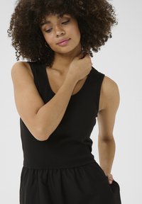Svart ribbad tanktop med V-ringning, figursydd kropp och något lös kjol. Mjuk kvalitet och elastisk midja för komfort.
