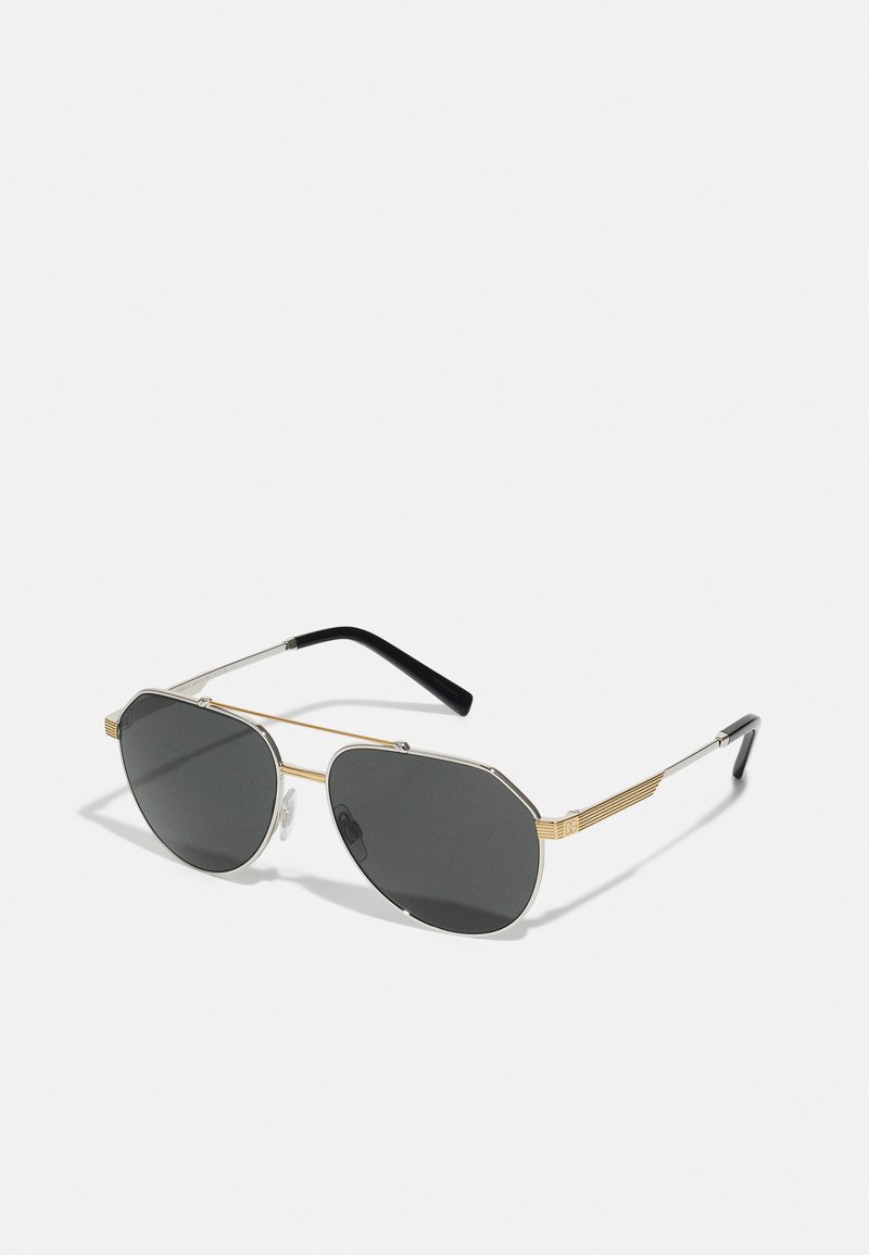 Gafas de sol con lentes grises octagonales, montura metálica en plata y oro, varillas delgadas en negro y acentos texturizados en la montura.