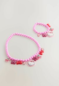Rosa pärlhalsband och armband med Hello Kitty-hängen, snören och blommor, placerade på en ljus bakgrund.