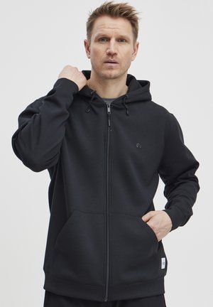 Zwarte zip-up hoodie van zachte stof, met een capuchon, voorkwabben en verstelbare trekkoorden. Minimalistisch ontwerp met een subtiel logo.