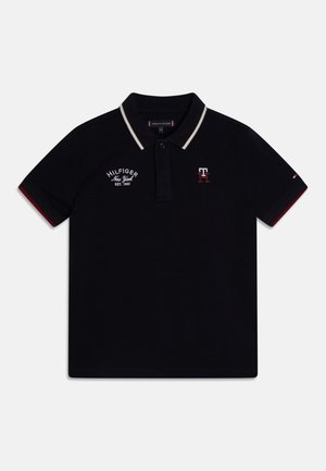 Polo noir à manches courtes avec bordure de col beige, patte de boutonnage, broderie "Hilfiger New York EST. 1985" et logo "TH" sur la poitrine.