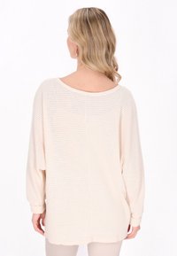 Pulover tricotat de culoare bej deschis, cu o croială lejeră, decolteu tip barcă și mâneci lungi. Prezintă un model texturat și un tiv rotund. Material moale.