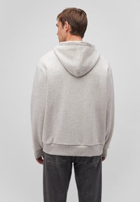 Light gray hooded sweatshirt made of soft, textured fabric. Features ribbed cuffs and hem, with a relaxed fit and minimalistic design.