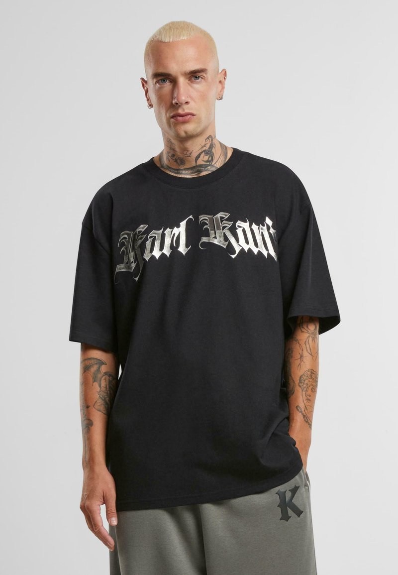 Black cotton t-shirt featuring a silver gothic-style "Karl Kani" graphic across the chest. Relaxed fit and short sleeves.