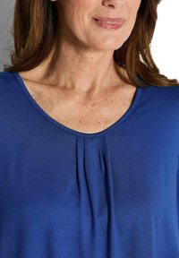 Königsblaues Oberteil mit Rundhals-Ausschnitt, das vertikale Falten in der Mitte vorne aufweist. Weicher Stoff mit glatter Textur.