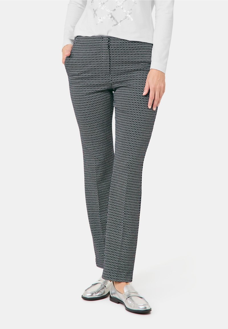 Pantaloni con motivo in bianco e nero dal taglio dritto, dotati di tasche laterali e indossati con mocassini argento. Tessuto dalla texture liscia.