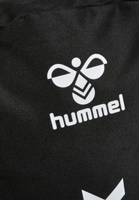 Zwarte stof met een witte gestileerde bijenlogo en het woord "hummel" eronder gedrukt op een textuurrijke materiaal.