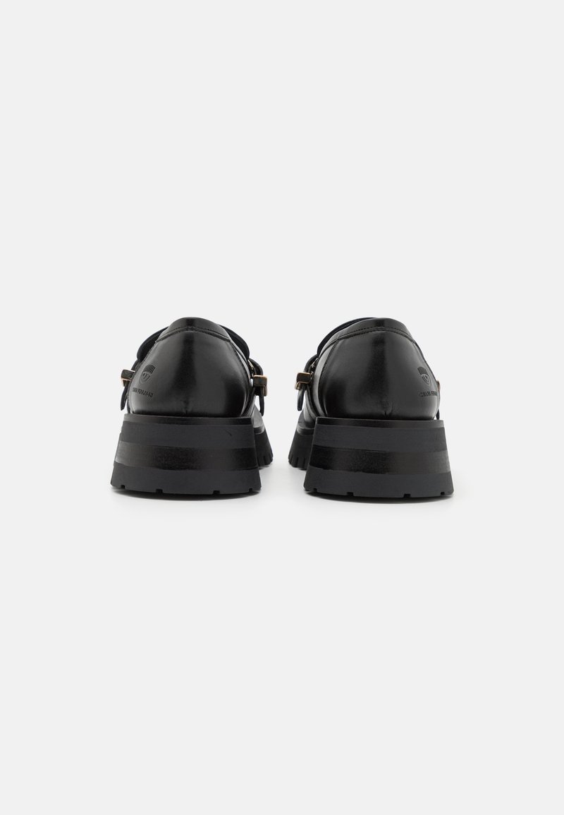 Chaussures en cuir noir avec une semelle épaisse, présentant une finition lisse, un design minimaliste et de subtils accents marron sur les lanières.