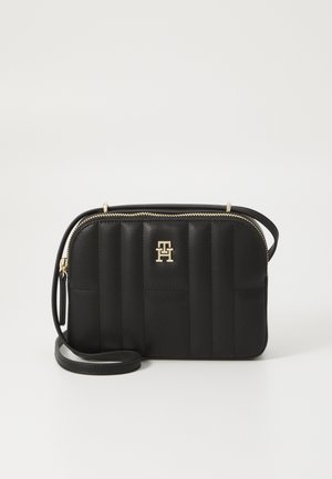 Mustmustreen mustriba kott, valmistatud sünteetilisest materjalist, kuldsete detailidega. Kotel on lukuga ja esiküljel logodekoratsioon.