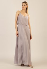 Faltendes Maxikleid in hellem Lavendel, mit dünnen Trägern und fließender Silhouette. Der Stoff hat eine weiche Textur mit einem subtilen Glanz.