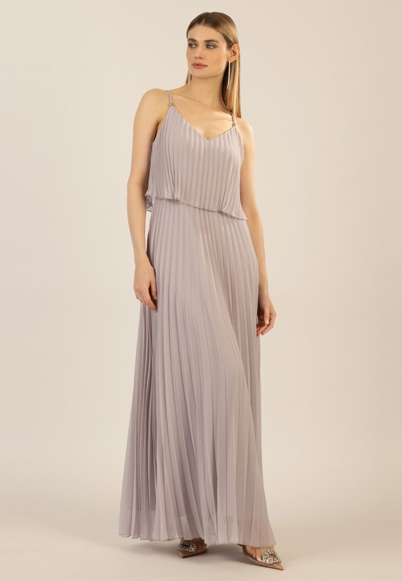 Faltendes Maxikleid in hellem Lavendel, mit dünnen Trägern und fließender Silhouette. Der Stoff hat eine weiche Textur mit einem subtilen Glanz.