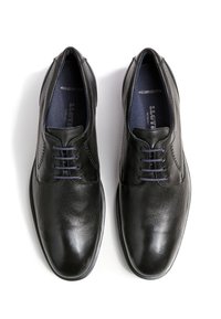 Zwarte leren schoenen met een gestructureerd oppervlak, ronde neus en vijf veterogen. Beschikt over een comfortabel voetbed en een gladde binnenvoering.