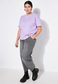 Lilla kortærmet t-shirt med 3D perleudsmykninger, parret med grå højtlivet jeans og kraftige sorte ankelstøvler.