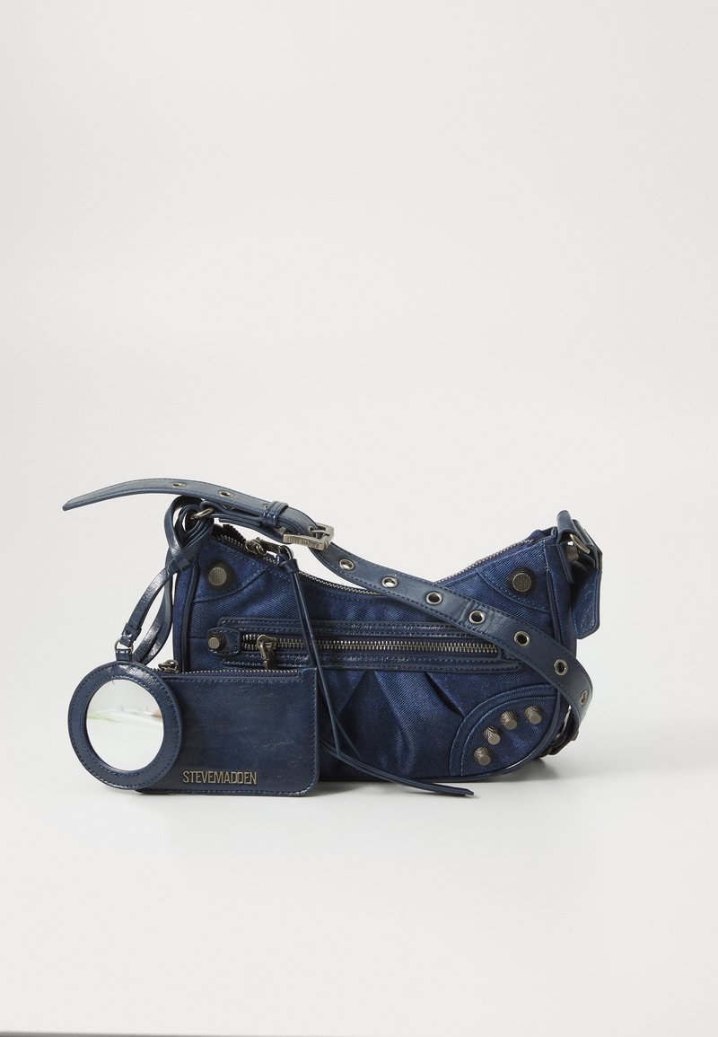 Navy denim crossbody bag with silver hardware, decorative studs, multiple zippered compartments, and an attached mirror.