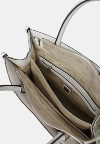 Borsa bianca con un'esterno texturizzato, caratterizzata da un interno beige con dettagli a motivo. Include scomparti con zip e aperti per un'organizzazione ottimale.