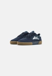 Marineblaue Sneaker aus Wildleder und Mesh, mit einer strukturierten Oberseite, weißen Logoakzenten und einer Gummisohle für besseren Halt.