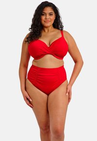 Conjunto de bikini rojo que incluye un top bandeau torcido y bragas de talle alto. La tela es suave con un ligero fruncido en los laterales.