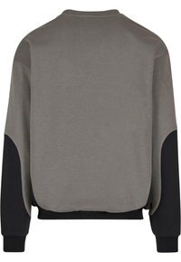 Sudadera de felpa gris con paneles laterales negros. Presenta un cuello redondo y puños acanalados. Textura suave, corte relajado y diseño minimalista.