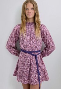 Vestido de leopardo púrpura con mangas largas, un escote alto, una falda acampanada y un detalle de cinturón azul tejido en la cintura.