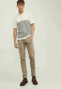Kortærmet polo shirt i creme med sorte vandrette striber, parret med beige slim-fit bukser og mørkebrune snørebåndssko.