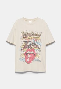 T-shirt écru avec le texte Rolling Stones 1975 Tour, présentant une grande bouche rouge avec langue et un oiseau volant au-dessus d’un fond de nuages.