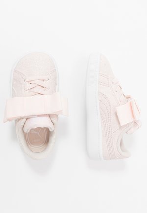 Paar hellrosa Kleinkind-Sneaker mit glitzernder Textur, weißen Sohlen, Schnürsenkeln und großen passenden Schleifen auf der Oberseite.