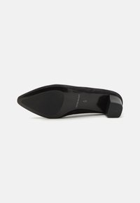 Black suede high heel shoe with a pointed toe and a chunky, textured heel. Branding on the sole is visible. Smooth surface.