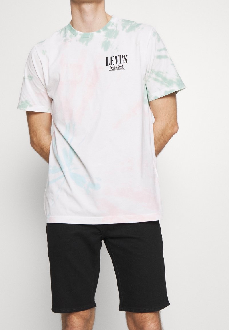 T-shirt in cotone bianca con motivi tie-dye verde e rosa, caratterizzata da un piccolo logo nero Levi’s sul petto. Maniche corte, vestibilità rilassata.