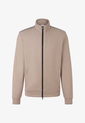 Beige Zip-Jacke mit Stehkragen, langen Ärmeln, zwei Fronttaschen und einem schwarzen Reißverschluss, der mittig vorne verläuft.