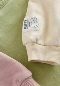 Tri dijela tkanine: svijetlozelena, nježno ružičasta i krem bijela. Krem bijela tkanina ima Miffy oznaku s jednostavnom grafikom zeca.
