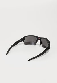 Czarne okulary przeciwsłoneczne o sportowym designie, z ciemnymi soczewkami, matowym wykończeniem i wygiętymi ramionami dla pewnego dopasowania. Wykonane z lekkiego materiału.