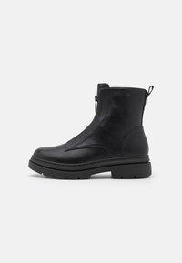 Bottes noires en cuir avec une texture lisse, bout rond, fermeture éclair sur le côté, et accents cousus sur une semelle épaisse et crantée.