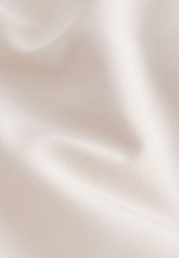 Šviesiai smėlio spalvos audinys su lygiu, šiek tiek tekstūruotu paviršiumi ir subtiliu blizgesiu. Lankstai ir raukšlės sukuria švelnias bangeles medžiagoje.