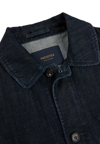 Kołnierz ciemnoniebieskiej kurtki z denimu z czarnymi guzikami, wewnątrz przy szyi widoczna metka marki "INCOTEX BLUE DIVISION".
