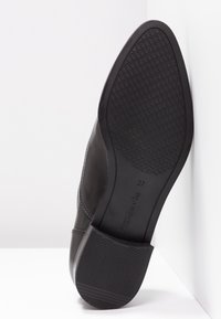 Semelle de chaussure habillée en cuir noir avec un motif de texture, taille 37, positionnée debout sur un fond blanc.