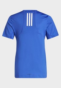 Camiseta deportiva azul con mangas cortas, cuello redondo y tres rayas blancas verticales en la parte trasera. Fabricada con tejido transpirable.