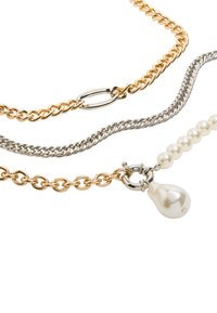 Trzy warstwowe łańcuszki: złoty łańcuszek, srebrny łańcuszek oraz łańcuszek z perłami, zakończony zawieszką w kształcie łzy.