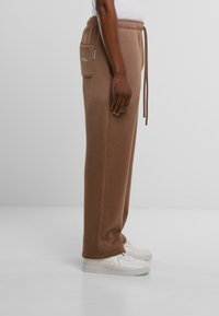 Braune Jogginghosen aus weichem Stoff, mit elastischem Bund, Kordelzug, seitlichen Taschen und einer lockeren Passform.