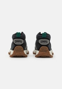 Black and green hiking shoes with a high-top design. Features rubber soles, embroidered branding, and textured fabric accents.