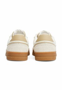 Sneaker bianche con accenti beige, realizzate in materiali sintetici lisci e suede testurizzato, con suole in gomma impregnate con "TOMMY JEANS."