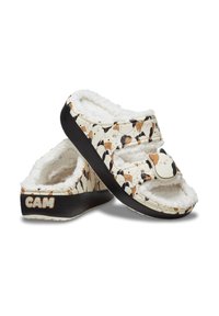 Chaussons avec une base blanche, ornés d'un motif de chien en marron et noir. Doublure douce et moelleuse avec des sangles ajustables et une semelle noire.