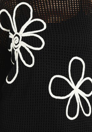 Schwarzer Mesh-Stoff mit großen, weißen, gestickten Gänseblümchenmotiven, die markante Umrisse und einfache Blütenblattformen aufweisen.