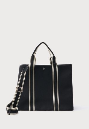 Czarna torba typu tote z dwoma krótkimi uchwytami i odpinanym, paskowanym paskiem na ramię, z pionowymi białymi paskami.