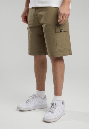 Khaki Cargo-Shorts mit zwei Seitentaschen, normaler Passform und glattem Baumwollstoff. Kombiniert mit weißen Sneakern und gerippten Socken.