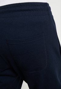 Marina blå joggers tillverkade av mjuk bomull med en enkel design, som har en öppen bakficka och resårmidja för komfort.