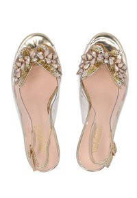 Transparante sandalen met een gouden metalen teenkap, decoratieve juweelstrik en een gewatteerde roze binnenzool. Inclusief verstelbare enkelband.